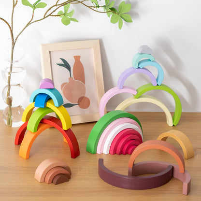 Colorful wooden arch toys on a wooden surface with a plant and framed picture in the background.