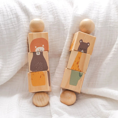 Two wooden block toys with animal illustrations on a white fabric background