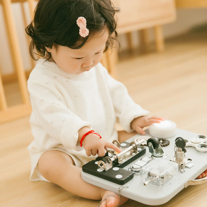 Child playing with busy board set on a wooden floor